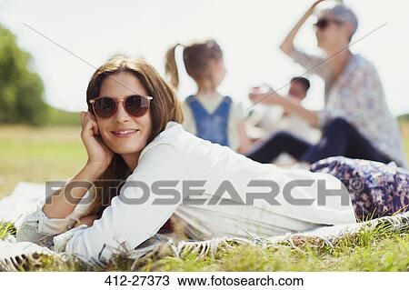 Portrait smiling woman laying on blanket in sunny field View Large Photo Image Stock Image - Portrait smiling woman laying on blanket in sunny field. Fotosearch