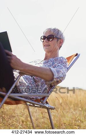 Senior woman reading book in sunny field View Large Photo Image Picture - Senior woman reading book in sunny field. Fotosearch