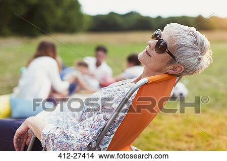 Senior woman relaxing in chair in field View Large Photo Image Picture - Senior woman relaxing in chair in field. Fotosearch