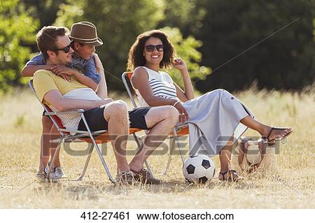 Stock Image - Smiling family relaxing in sunny field. Fotosearch