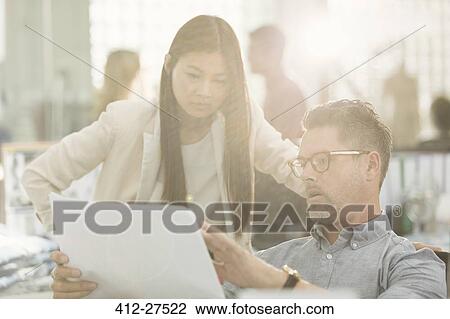 Business people discussing paperwork in office View Large Photo Image Stock Image - Business people discussing paperwork in office. Fotosearch