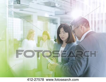 Stock Photo - Business people discussing paperwork in office. Fotosearch