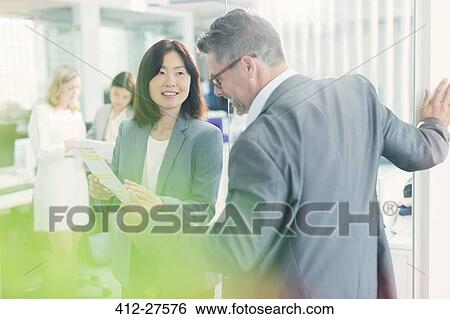 Stock Photograph - Business people discussing paperwork in office. Fotosearch