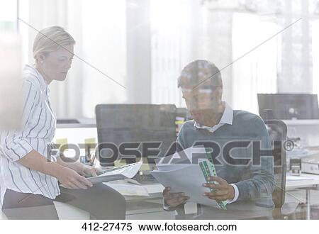 Business people reviewing paperwork at desk in office View Large Photo Image Stock Photography - Business people reviewing paperwork at desk in office. Fotosearch