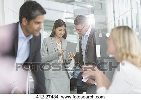 Business people sharing digital tablet in conference room View Large Photo Image Picture - Business people sharing digital tablet in conference room. Fotosearch