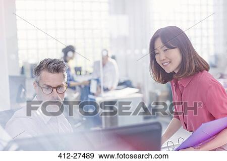 Stock Photo - Business people using computer at desk in office. Fotosearch