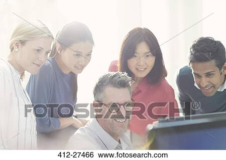 Business people working at computer in sunny office View Large Photo Image Stock Photograph - Business people working at computer in sunny office. Fotosearch