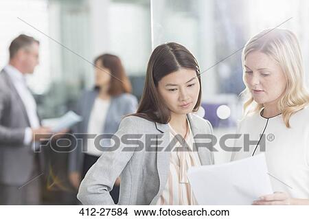 Businesswomen discussing paperwork in office View Large Photo Image Picture - Businesswomen discussing paperwork in office. Fotosearch