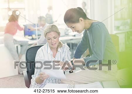 Businesswomen discussing paperwork in office View Large Photo Image Stock Photography - Businesswomen discussing paperwork in office. Fotosearch