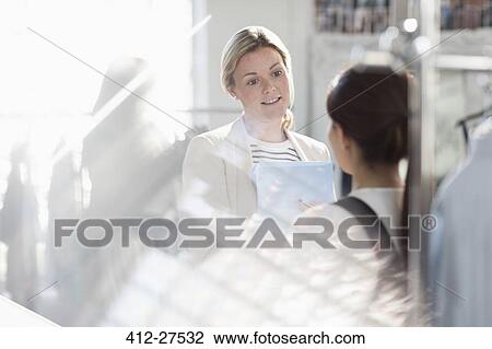 Businesswomen talking in sunny office View Large Photo Image Stock Image - Businesswomen talking in sunny office. Fotosearch