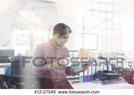 Stock Photo - Fashion designer drinking coffee using digital tablet in office. Fotosearch