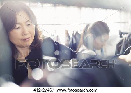 Stock Photo - Fashion designer examining clothing on rack. Fotosearch