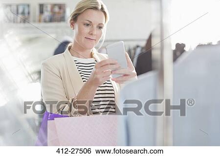 Stock Photograph - Fashion designer photographing clothing with camera phone. Fotosearch