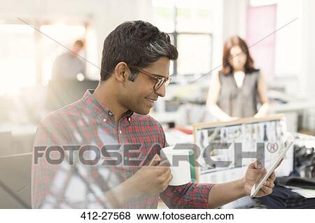 Fashion designer using digital tablet and drinking coffee in office View Large Photo Image Stock Photo - Fashion designer using digital tablet and drinking coffee in office. Fotosearch
