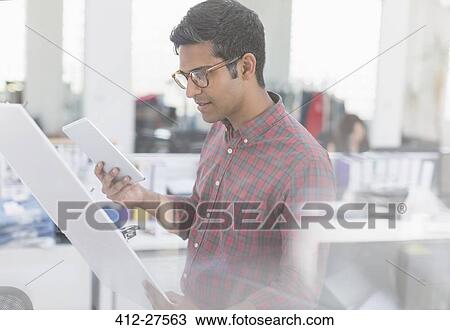 Fashion designer with digital tablet examining story board in office View Large Photo Image Stock Image - Fashion designer with digital tablet examining story board in office. Fotosearch