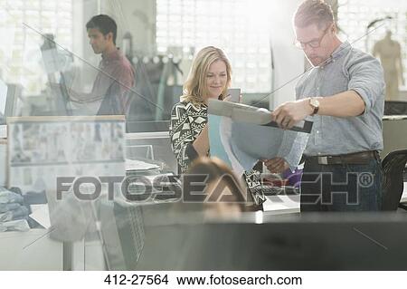 Picture - Fashion designers examining fabric in office. Fotosearch