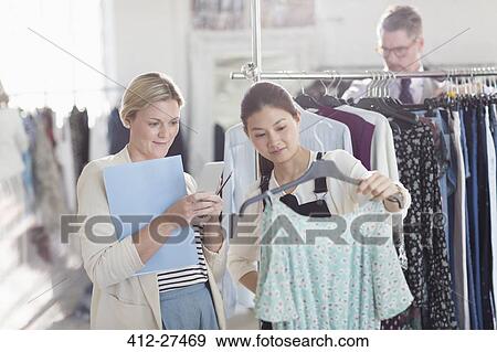 Fashion designers photographing dress with camera phone View Large Photo Image Stock Photo - Fashion designers photographing dress with camera phone. Fotosearch