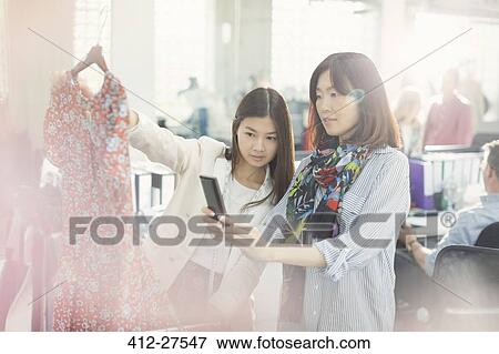 Stock Photo - Fashion designers photographing dress with camera phone. Fotosearch