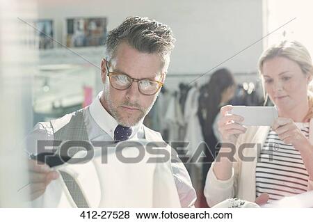 Fashion designers photographing clothing with camera phone View Large Photo Image Stock Photo - Fashion designers photographing clothing with camera phone. Fotosearch