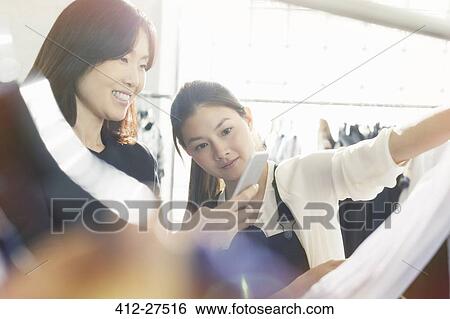 Stock Photograph - Fashion designers photographing clothing with camera phone. Fotosearch