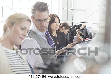 Fashion designers reviewing clothing on racks View Large Photo Image Picture - Fashion designers reviewing clothing on racks. Fotosearch