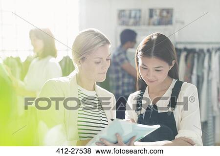 Stock Photo - Fashion designers reviewing paperwork in office. Fotosearch