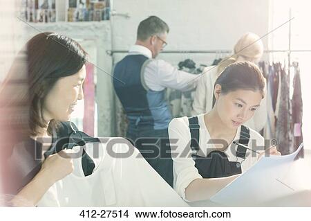 Picture - Fashion designers taking notes on clothing. Fotosearch