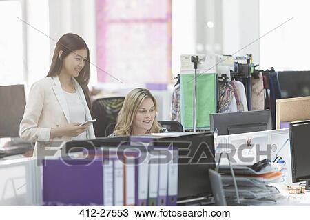 Fashion designers working at computer at desk in office View Large Photo Image Stock Image - Fashion designers working at computer at desk in office. Fotosearch