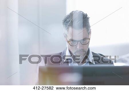 Stock Image - Focused businessman using computer in office. Fotosearch