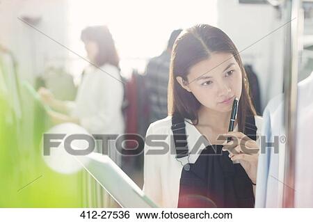 Pensive fashion designer examining shirt View Large Photo Image Stock Photograph - Pensive fashion designer examining shirt. Fotosearch