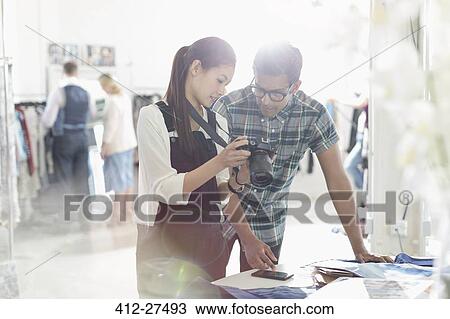 Photographer and fashion designer looking down at camera in sunny office View Large Photo Image Stock Image - Photographer and fashion designer looking down at camera in sunny office. Fotosearch