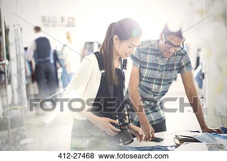 Photographer and fashion designer viewing proofs in sunny office View Large Photo Image Stock Photo - Photographer and fashion designer viewing proofs in sunny office. Fotosearch