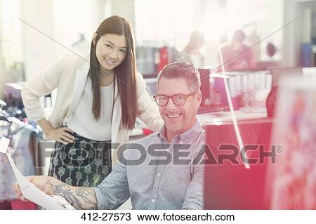 Stock Image - Portrait smiling fashion designers reviewing paperwork in office. Fotosearch