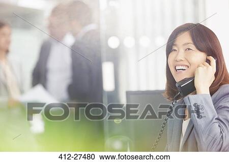 Smiling businesswoman talking on telephone in office View Large Photo Image Stock Image - Smiling businesswoman talking on telephone in office. Fotosearch
