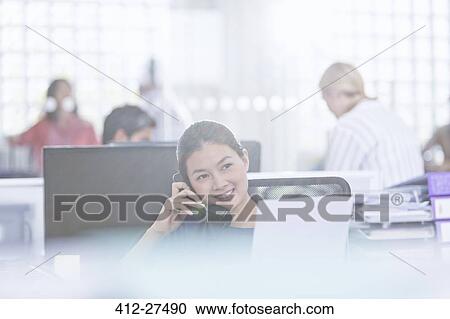 Smiling businesswoman talking on telephone in office View Large Photo Image Stock Image - Smiling businesswoman talking on telephone in office. Fotosearch