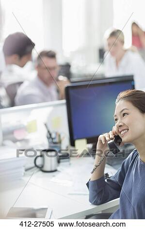 Smiling businesswoman talking on telephone at desk in office View Large Photo Image Stock Photography - Smiling businesswoman talking on telephone at desk in office. Fotosearch