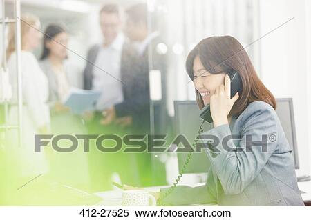 Smiling businesswoman talking on telephone in office View Large Photo Image Stock Photography - Smiling businesswoman talking on telephone in office. Fotosearch