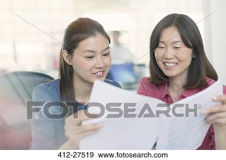 Smiling businesswomen discussing paperwork in office View Large Photo Image Stock Photo - Smiling businesswomen discussing paperwork in office. Fotosearch