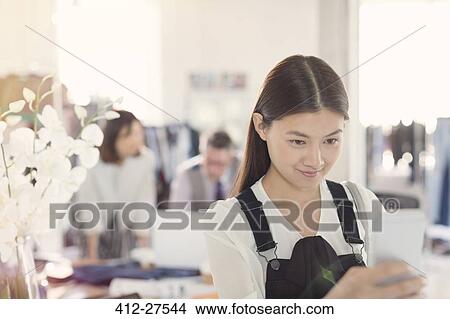 Smiling fashion designer texting with cell phone View Large Photo Image Picture - Smiling fashion designer texting with cell phone. Fotosearch
