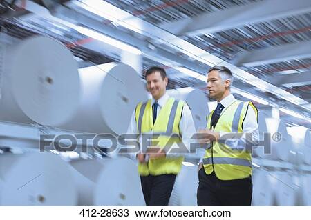 Businessmen in reflective clothing walking along large paper spools in printing plant View Large Photo Image Stock Image - Businessmen in reflective clothing walking along large paper spools in printing plant. Fotosearch