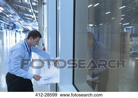 Engineer reviewing blueprints in factory View Large Photo Image Stock Photo - Engineer reviewing blueprints in factory. Fotosearch