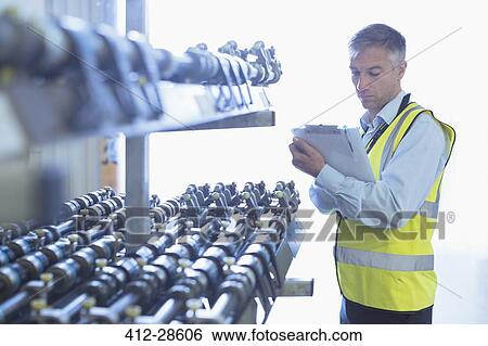 Engineer with clipboard checking printing press conveyor belt View Large Photo Image Stock Photograph - Engineer with clipboard checking printing press conveyor belt. Fotosearch