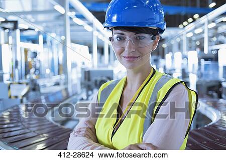 Picture - Portrait confident female worker with hard-hat and protective eyewear in factory. Fotosearch