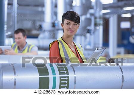 Stock Image - Portrait confident female worker with clipboard in factory. Fotosearch