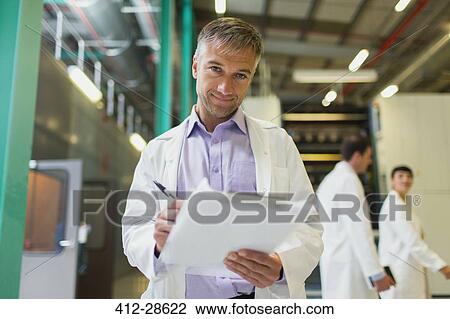 Stock Image - Portrait confident scientist with clipboard in factory. Fotosearch