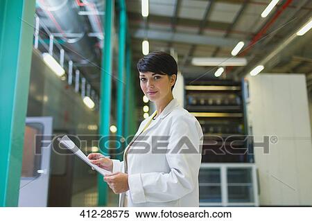 Stock Photography - Portrait confident scientist with paperwork in factory. Fotosearch