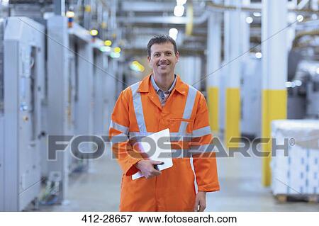 Stock Photo - Portrait confident worker in reflective clothing with clipboard in factory. Fotosearch