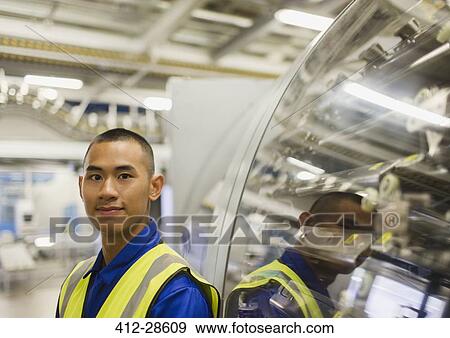 Stock Photo - Portrait confident worker leaning on machinery in factory. Fotosearch