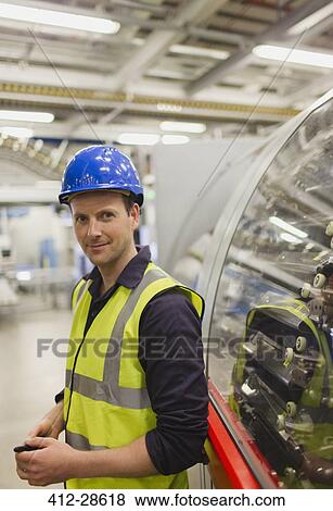 Stock Photo - Portrait confident worker leaning on machinery in factory. Fotosearch