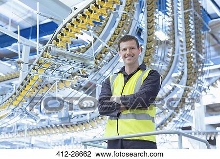 Portrait confident worker standing below printing press conveyor belts overhead View Large Photo Image Stock Image - Portrait confident worker standing below printing press conveyor belts overhead. Fotosearch